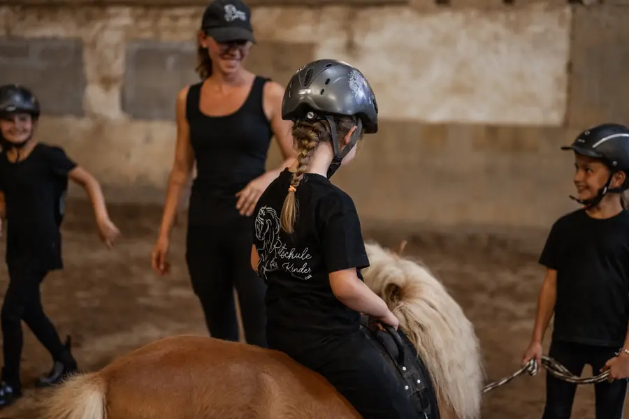 Franziska Falk unterrichtet eine Gruppe Kinder mit einem Pony in der Reithalle.